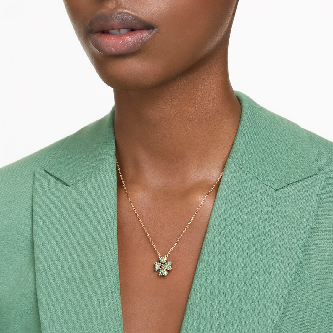 Swarovski Idyllia pendant featuring a green clover design with gold-tone plating, sparkling crystal details, and a delicate chain.