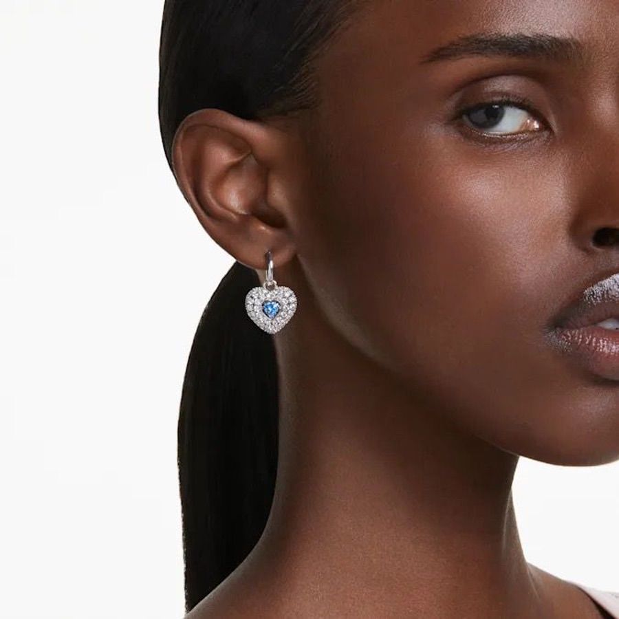 Swarovski Hyperbola Drop Earrings with heart-shaped blue crystals and rhodium plating, showcasing elegant jewelry design.
