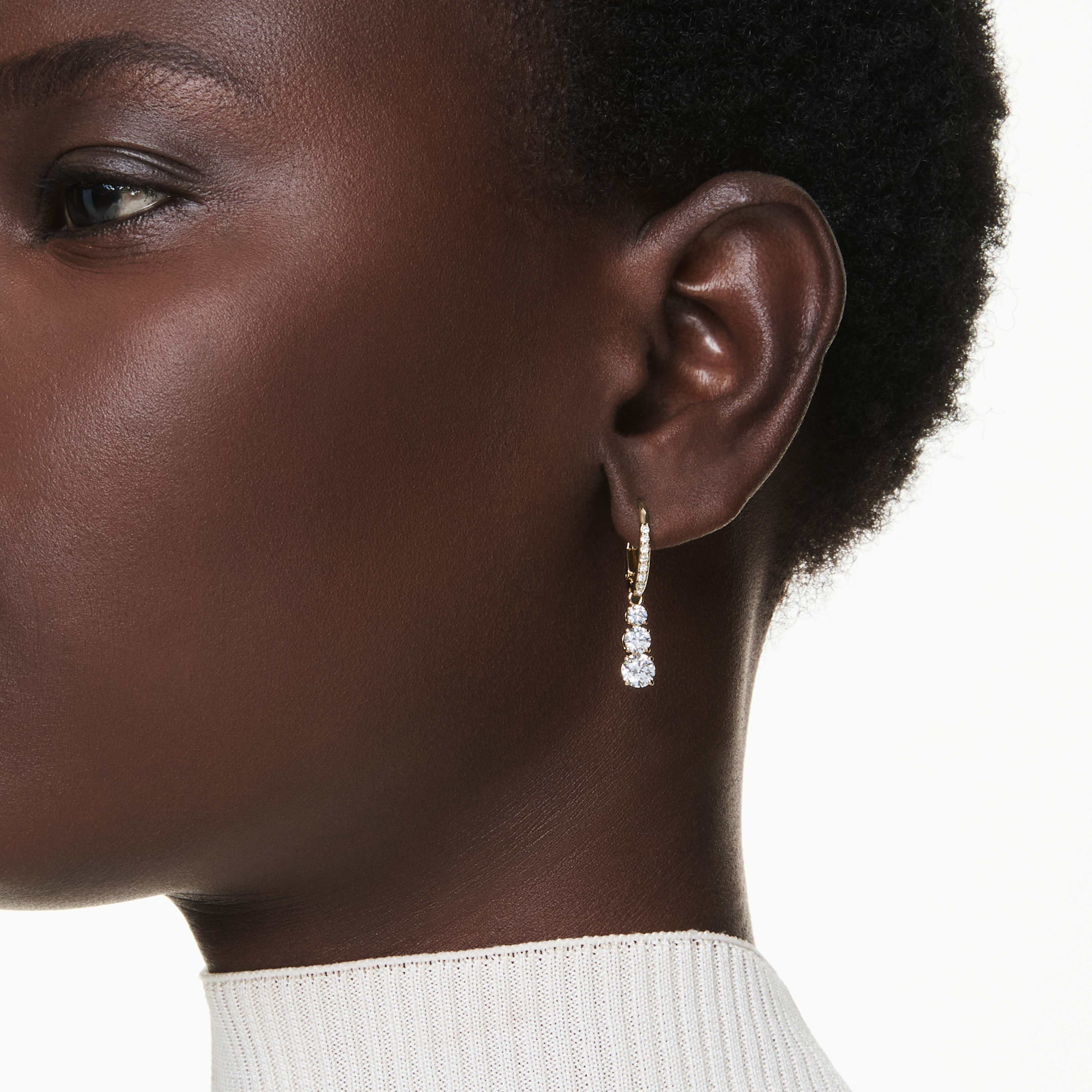 Swarovski Stilla Attract hoop earrings with round white crystals and gold-tone plating, showcasing elegant jewelry design.