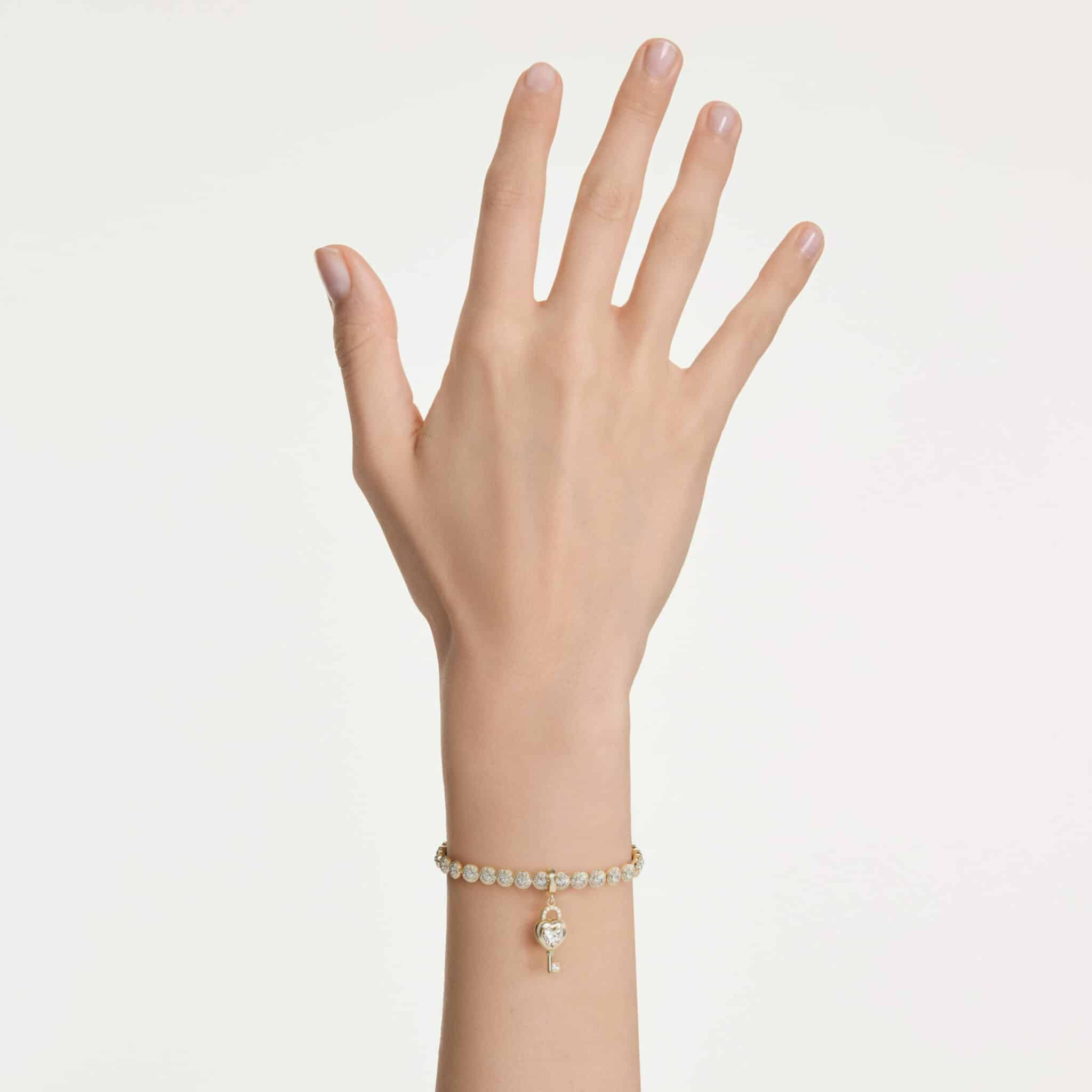 Swarovski Idyllia charm with mixed cuts, heart and key design in white with gold-tone plating, for jewelry or charm bracelets.