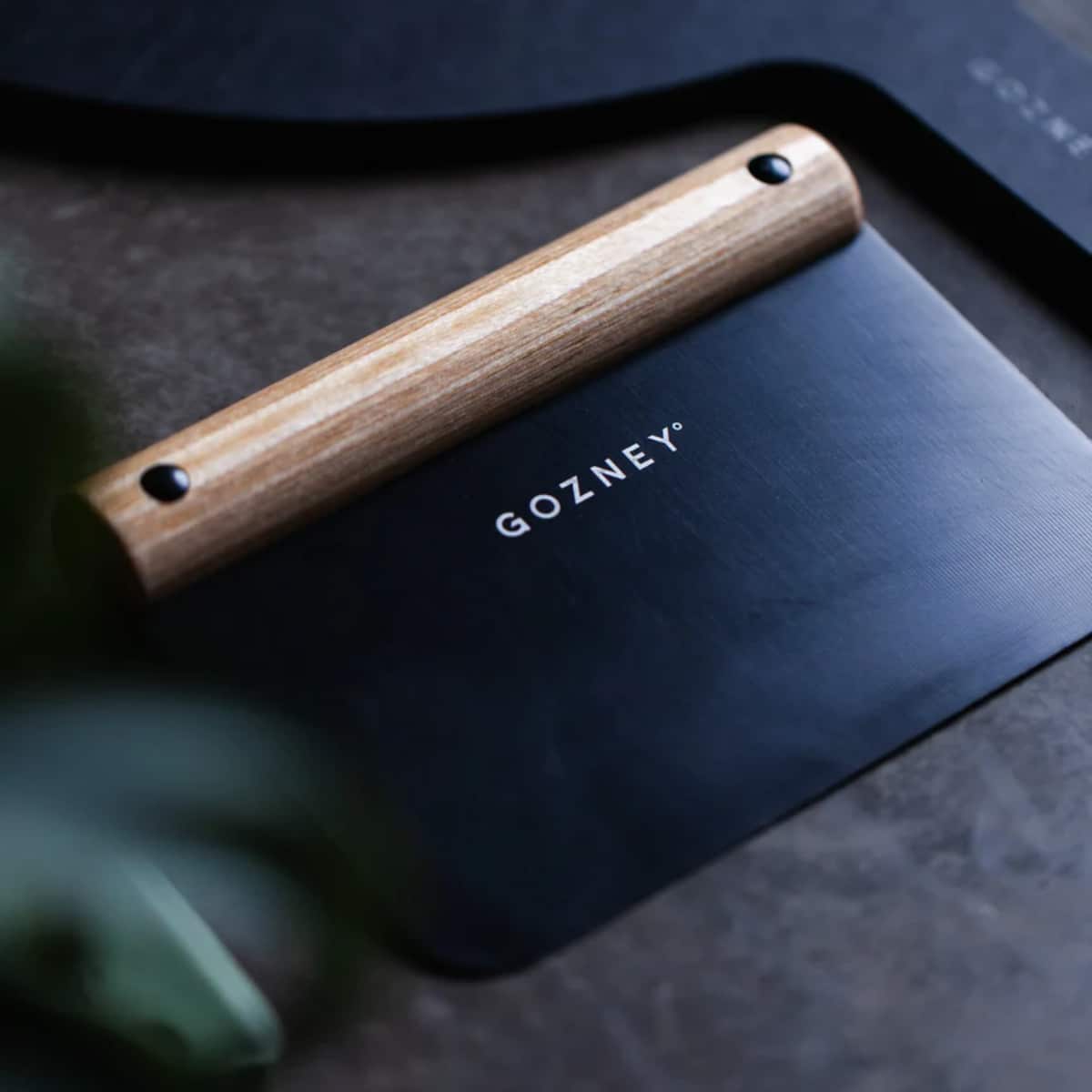 Gozney Dough Cutter with wooden handle and stainless steel blade for precise pizza and bread dough slicing.