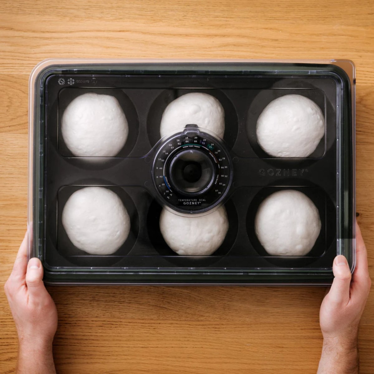 Gozney Dough Tray with a wooden handle holding freshly prepared pizza dough on a stainless steel tray.