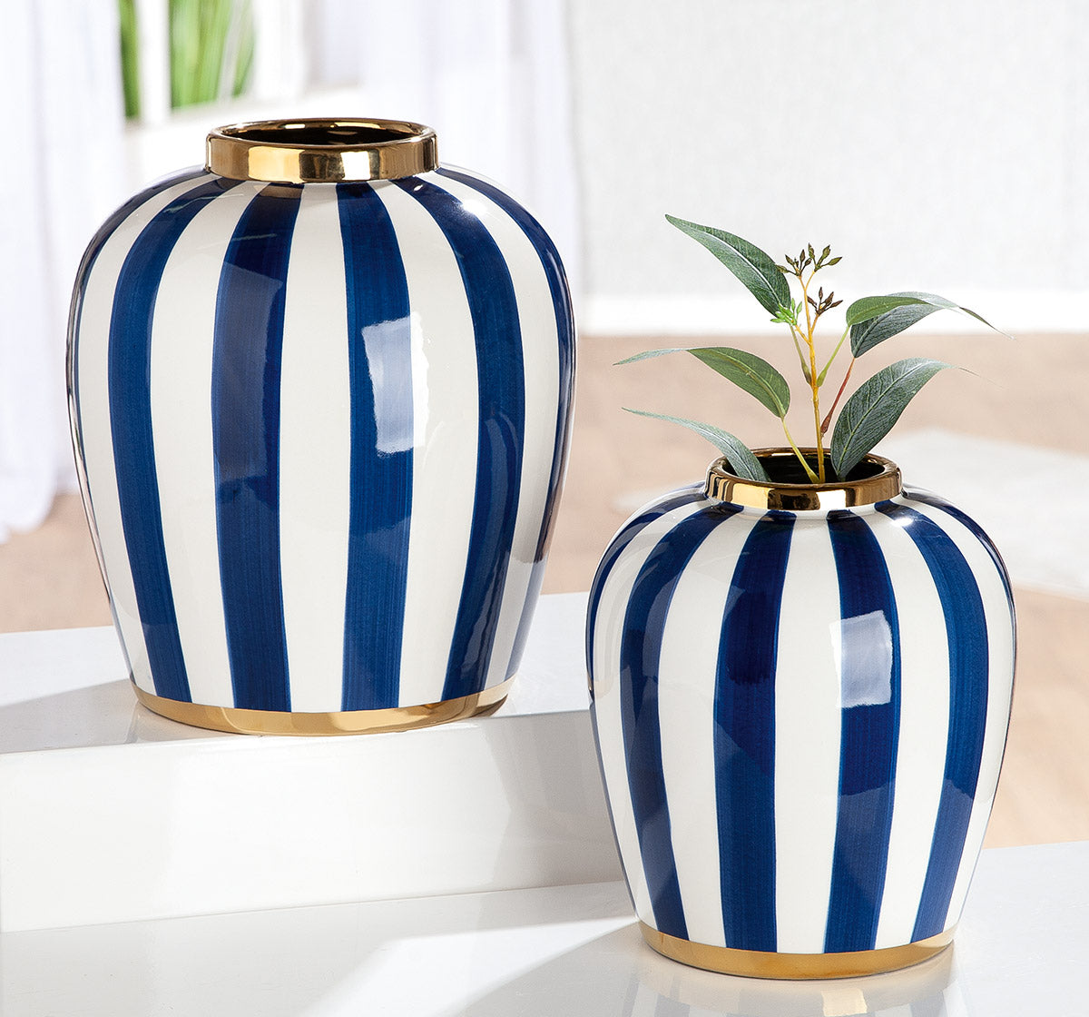 Blue and white bulbous ceramic Gilde Elio vase with striped design on a plain background.