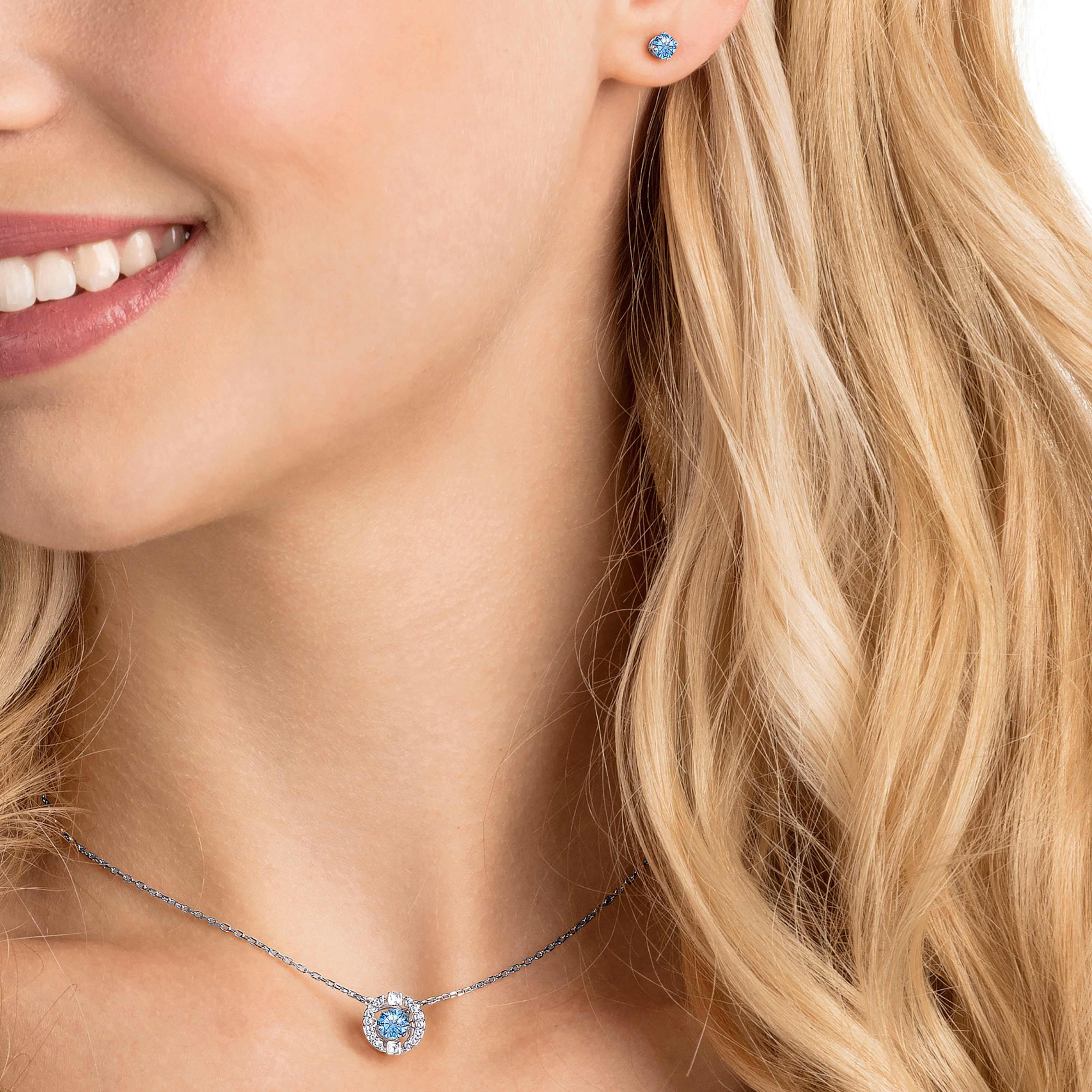Swarovski Una set with round-cut blue crystals and rhodium-plated jewelry pieces, featuring elegant, sparkling designs.