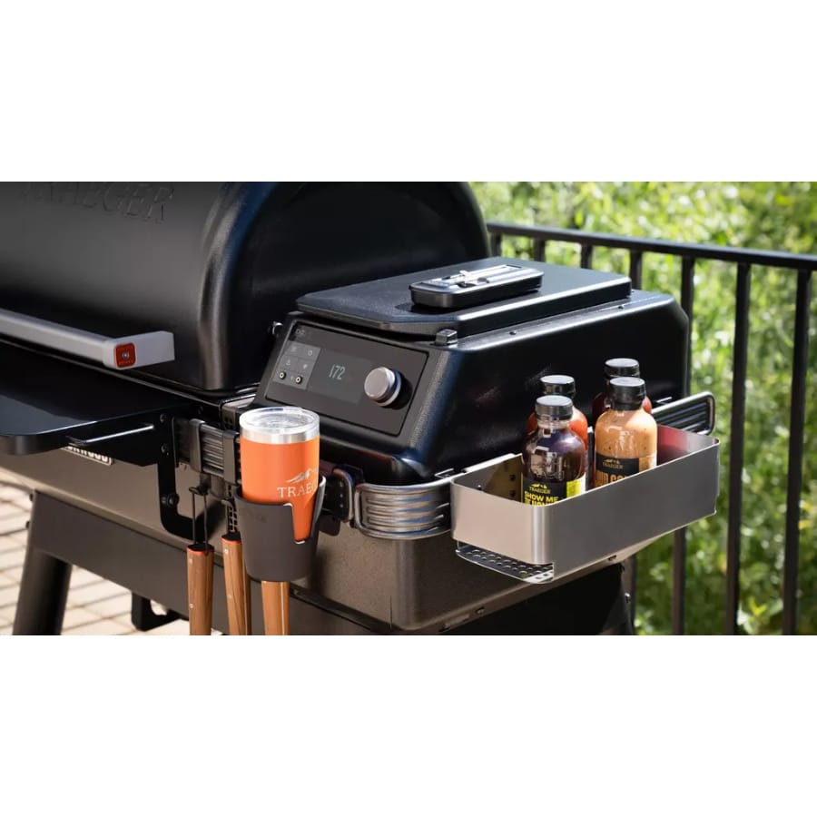 Traeger Ironwood wood pellet grill with accessories, outdoor cooking setup, stainless steel finish, and grilling tools on a patio.