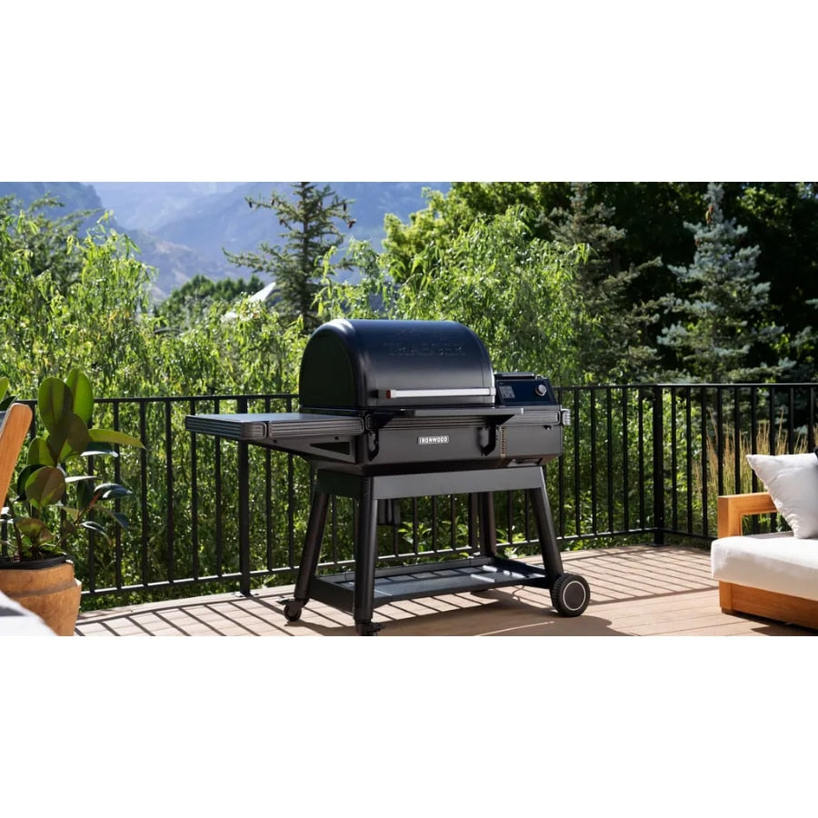 Traeger Ironwood wood pellet grill outdoors with cooking surface, digital controls, and wood pellet hopper in a backyard setting.